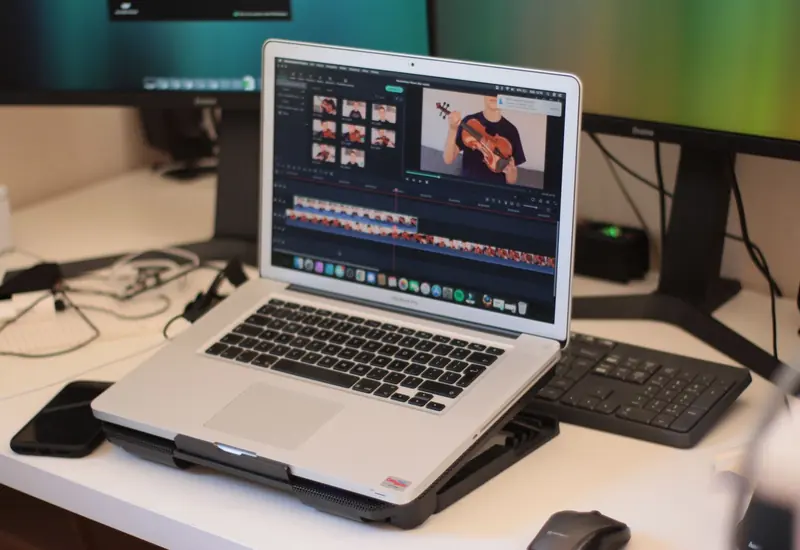 Laptop sobre un escritorio muestra una biblioteca de videos en miniatura y una línea de edición