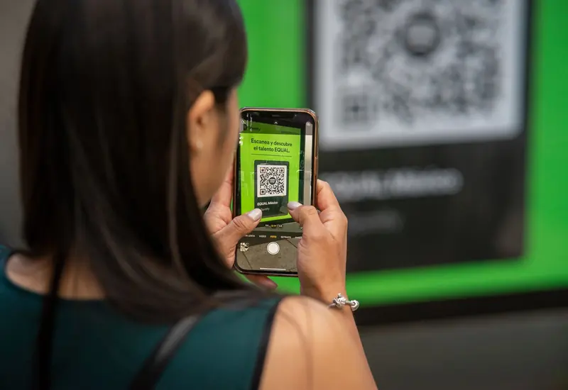 Mujer escanea con su celular un código QR impreso en un cartel